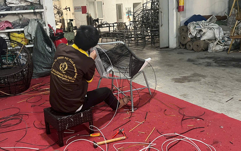 Hình ảnh người thợ thực hiện công đoạn đan ghế bằng sợi mây nhựa tròn cao cấp